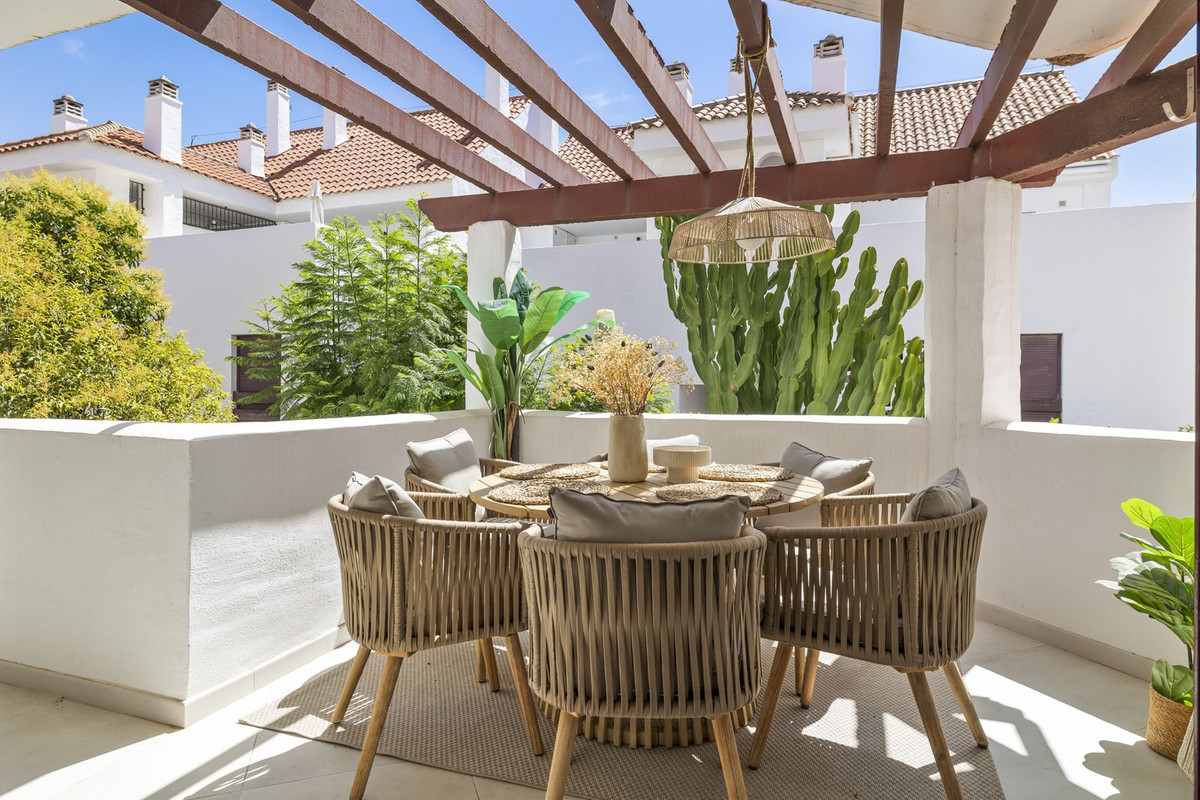 Private covered terrace with pergola, round dining table and garden views, La Maestranza, Nueva Andalucía