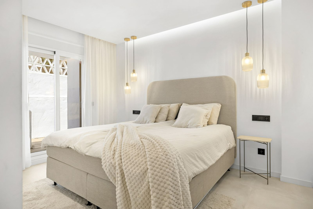 Master bedroom with upholstered headboard and doors to a private patio